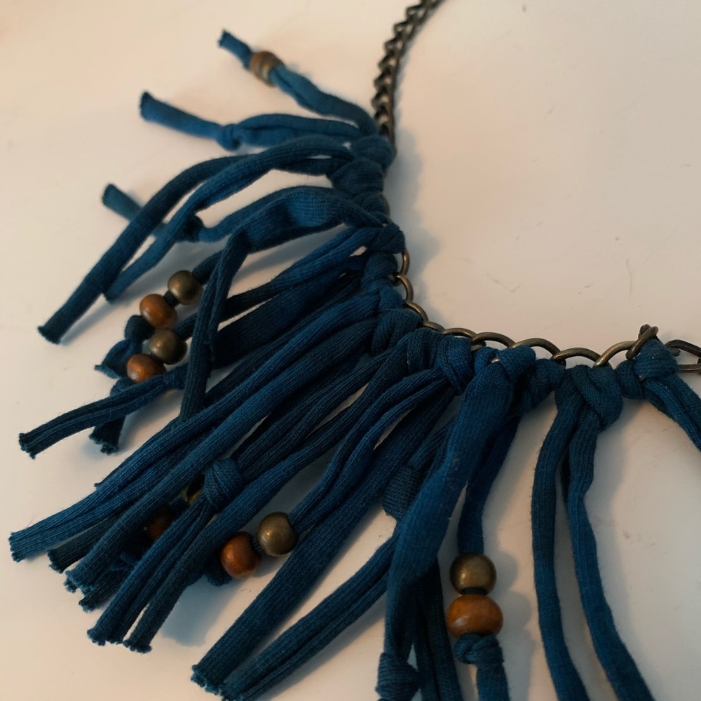 Chain necklace with blue cloth fringe.